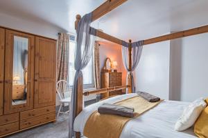 a bedroom with a four poster bed and a dresser at Castle View - Charming cottage with views of Dover Castle in Kent