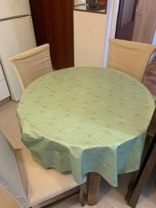 stół z zieloną tkaniną na górze dwóch krzeseł w obiekcie Apartment Emma w mieście Rijeka