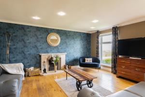 un soggiorno con un divano e una TV di Alton Villa, Sleeps 12, Great for Families, Undercover Hotub & Games Room a Newmilns