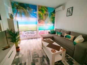 ein Wohnzimmer mit einem Sofa und einem Palmenmilch in der Unterkunft Apartamento Alhóndiga El Palo in Málaga