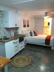 a kitchen and a bedroom with a bed and a sink at Lala Pansie in Stilbaai