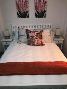 a bed with two pillows on it with two night stands at Lala Pansie in Stilbaai