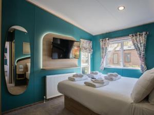 a bedroom with a large bed with a mirror at Golden Sands Holiday Park in Kinmel Bay +39 photos