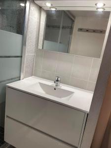 een badkamer met een witte wastafel en een spiegel bij Pavillon à 400m de la plage avec piscine in Valras-Plage
