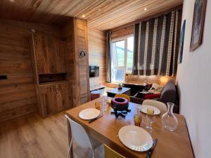 una sala da pranzo con tavolo in legno e un soggiorno di OURS BLANC 29 duplex avec vue a La Clusaz