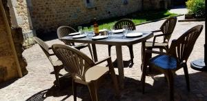 een tafel met stoelen en een fles wijn erop bij Le gîte des remparts au cœur du village médiéval in Le Malzieu-Ville