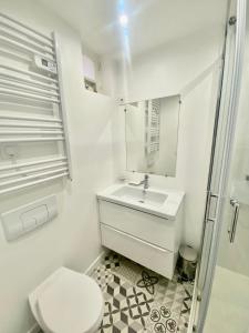 een witte badkamer met een wastafel en een toilet bij Charmante maison au coeur de Villerville in Villerville
