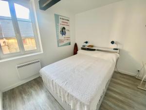 een slaapkamer met een wit bed en een raam bij Charmante maison au coeur de Villerville in Villerville