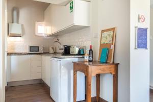 a small kitchen with white cabinets and a wooden table at Kochab Sintra by LovelyStay in Sintra