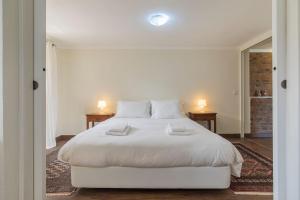 a bedroom with a large white bed with two lamps at Kochab Sintra by LovelyStay in Sintra