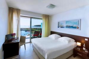 una camera d'albergo con letto, scrivania e finestra di Royal Antibes - Luxury Hotel, Résidence, Beach & Spa a Antibes