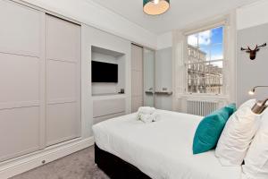 a white bedroom with a bed and a window at Modern & Spacious 1 Bed Apt, West End in Edinburgh