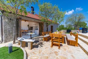 a patio with a table and chairs and a house at New! Promina luxury villa with 72sqm Heated Pool, Jacuzzi, Infrared Sauna, Tennis court, Media room in Bogatić