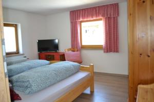 a bedroom with two beds and a window and a television at Goldiger Hirsch in Immenstadt im Allgäu