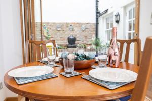 a wooden table with plates and a bottle of wine at 17 Rodney Road - Luxury Apartments in Cheltenham