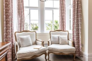 2 sillas frente a una ventana con cortinas en St Marys Hall Hotel, en Hugh Town
