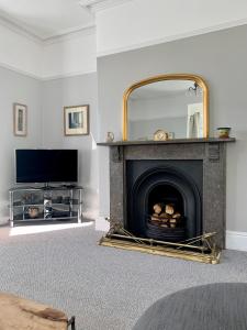 a living room with a fireplace and a mirror at Crescent Bank in Buxton