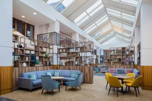 a library with a blue couch and chairs and tables at Ashford International Hotel & Spa in Ashford