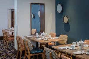 a dining room with tables and chairs and mirrors at Ashford International Hotel & Spa in Ashford