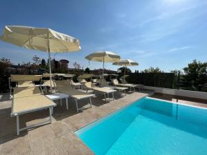 - une piscine bordée de chaises longues et de parasols dans l'établissement Hotel Renata, à Lazise