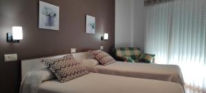 pokój hotelowy z dwoma łóżkami i krzesłem w obiekcie Hotel Grove w mieście O Grove