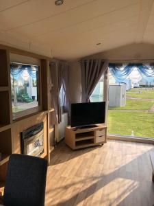 a living room with a television and a fireplace at Flosh Caravan, Manor House Park in Mawbray