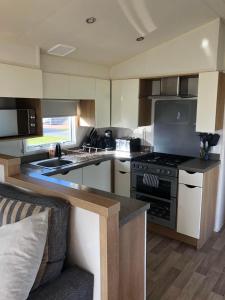 a kitchen with a stove and a couch in it at Flosh Caravan, Manor House Park in Mawbray