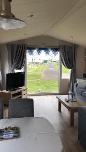 a living room with a couch and a table and a tv at Flosh Caravan, Manor House Park in Mawbray