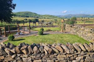 a stone wall with a playground in a field at Mountain View in Ulverston