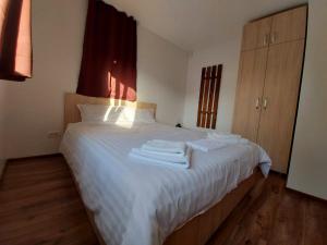 Un dormitorio con una cama blanca con toallas. en C House en Buşteni