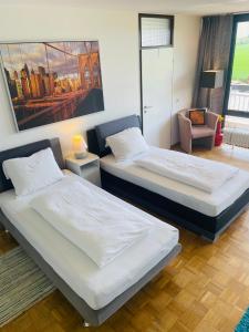 een kamer met 2 bedden en een stoel. bij Messe Apartment Köln West in Keulen