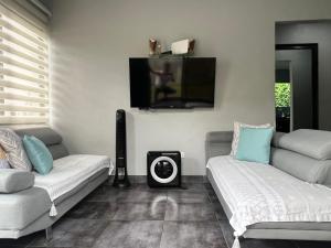 a living room with two couches and a flat screen tv at Casa Laureles in Guápiles