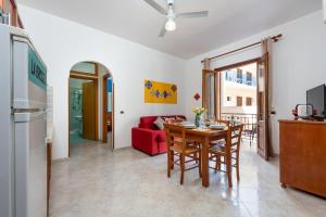 a kitchen and living room with a table and a red couch at I Tre Golfi Beach Apartments in San Vito lo Capo