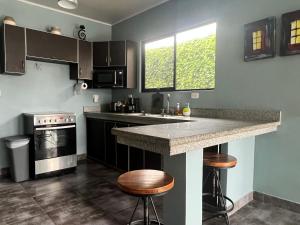 a kitchen with a counter and some stools in it at Casa Laureles in Guápiles