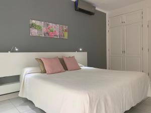 ein Schlafzimmer mit einem großen weißen Bett mit rosa Kissen in der Unterkunft Vivienda Tauro in Puerto del Carmen