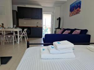 a living room with a blue couch and towels on a bed at Anna24 Holidays in Vantačići
