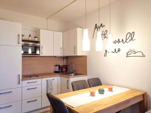 Jonas Deluxe Apartment Panoramablick في باد غويسرن: مطبخ مع طاولة خشبية ومطبخ مع دواليب بيضاء