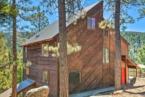 a wooden house in the woods with trees at Roomy Angel Fire Home with Hot Tub, Sunroom and Views! in Angel Fire