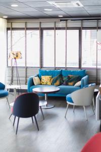 ein Wohnzimmer mit einem blauen Sofa, Tischen und Fenstern in der Unterkunft ibis Toulouse Université in Toulouse