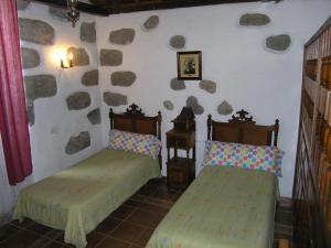 2 camas en una habitación con rocas en la pared en La Casita de Andres 1 en Agüimes