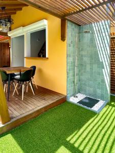 eine Terrasse mit einer Dusche, einem Tisch und grünem Gras in der Unterkunft Bungalow Au coeur de la nature in Petit-Bourg