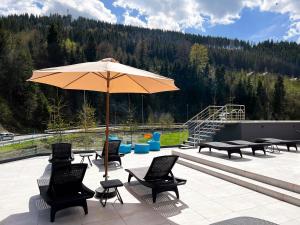 a patio with an umbrella and chairs and tables at Hotel Skilandhouse in Bukovel