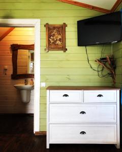 a bathroom with a white dresser with a television on the wall at Садиба "ОРНАМЕНТ" in Szack