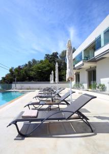 una fila di sedie a sdraio e ombrelloni accanto alla piscina di ALMYRA seafront residence a Lygia