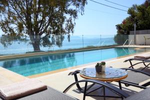 una mesa y sillas junto a una piscina en ALMYRA seafront residence en Lygia