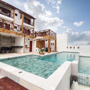 a swimming pool in front of a house with water at Pousada Via do Sol - Icaraí de Amontada in Icaraí