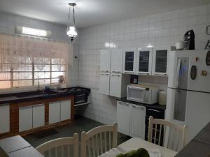 a kitchen with white appliances and a table with chairs at CHACARA VALE DOS SONHOS ITU Chacara de Condominio in Itu