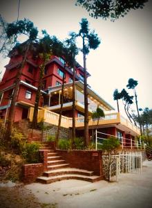 un grand bâtiment rouge avec des palmiers devant lui dans l'établissement Mount Everest Hotel & Resort Nagarkot, à Nagarkot