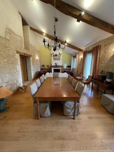 una gran sala de estar con mesa de madera y sillas. en LA FERME DE VILLENEUVE en Saint-Antoine