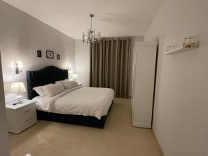a bedroom with a large bed and a chandelier at سافانا امواج Amwaj savana in Half Moon Bay +26 photos